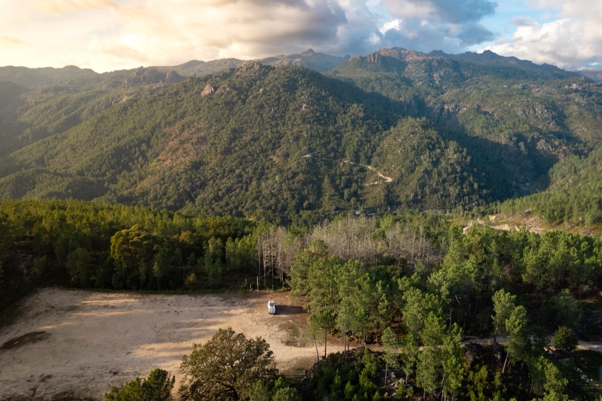 Campervan parked on a hilltop above the clouds at golden hour