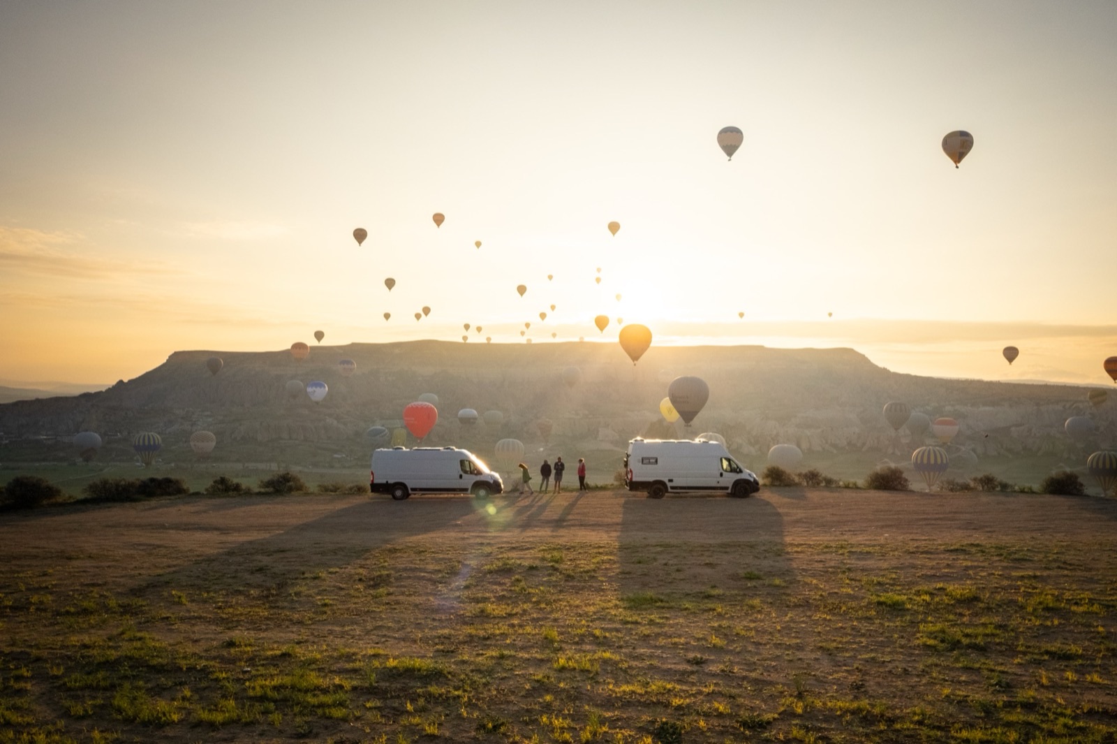 Aerial view of a campervan on a mountain road surrounded by pine trees